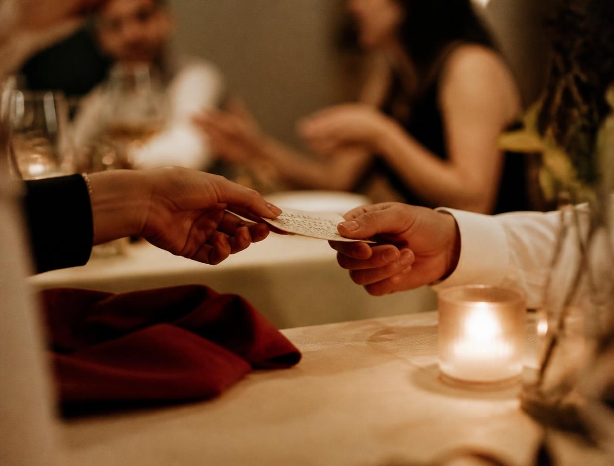 Une main tend un petit mot écrit à la main au-dessus d'une nappe crème
